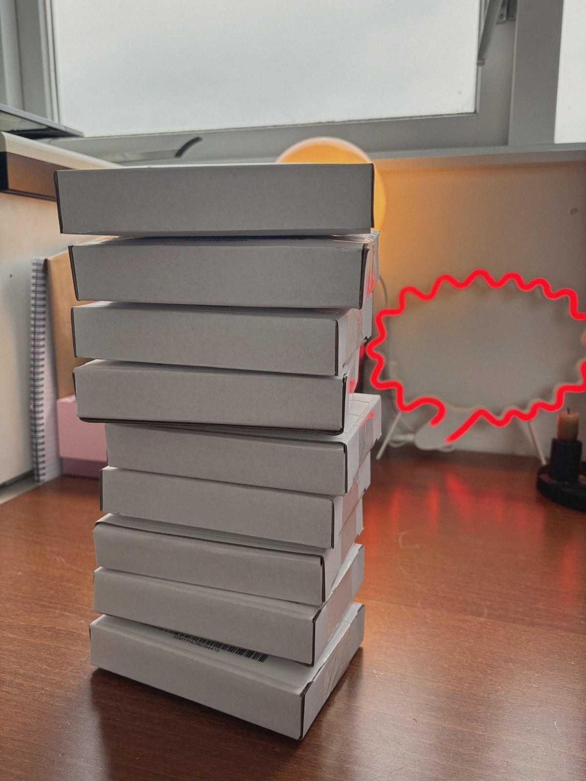 A tall stack of shipping boxes with finished Babbel Games on a desk by the window
