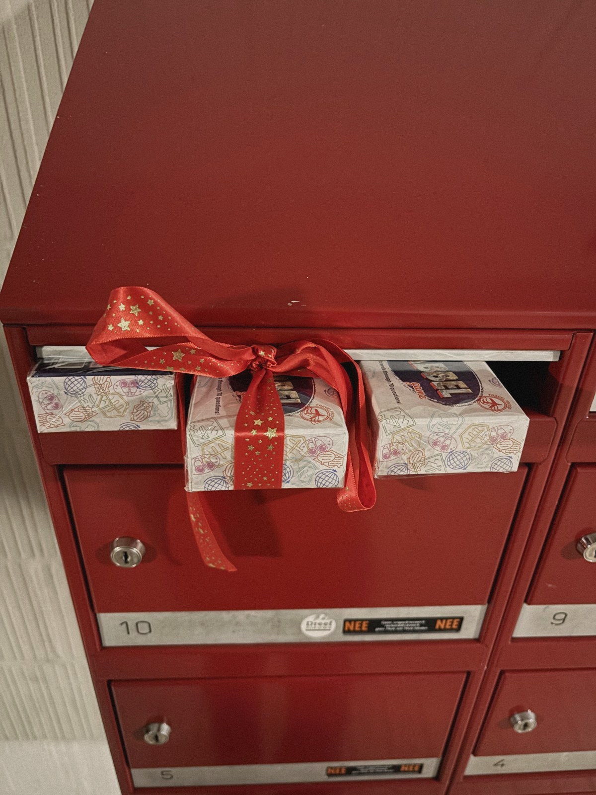 Babbel Game boxes in a red mailbox locker, one wrapped with a red ribbon