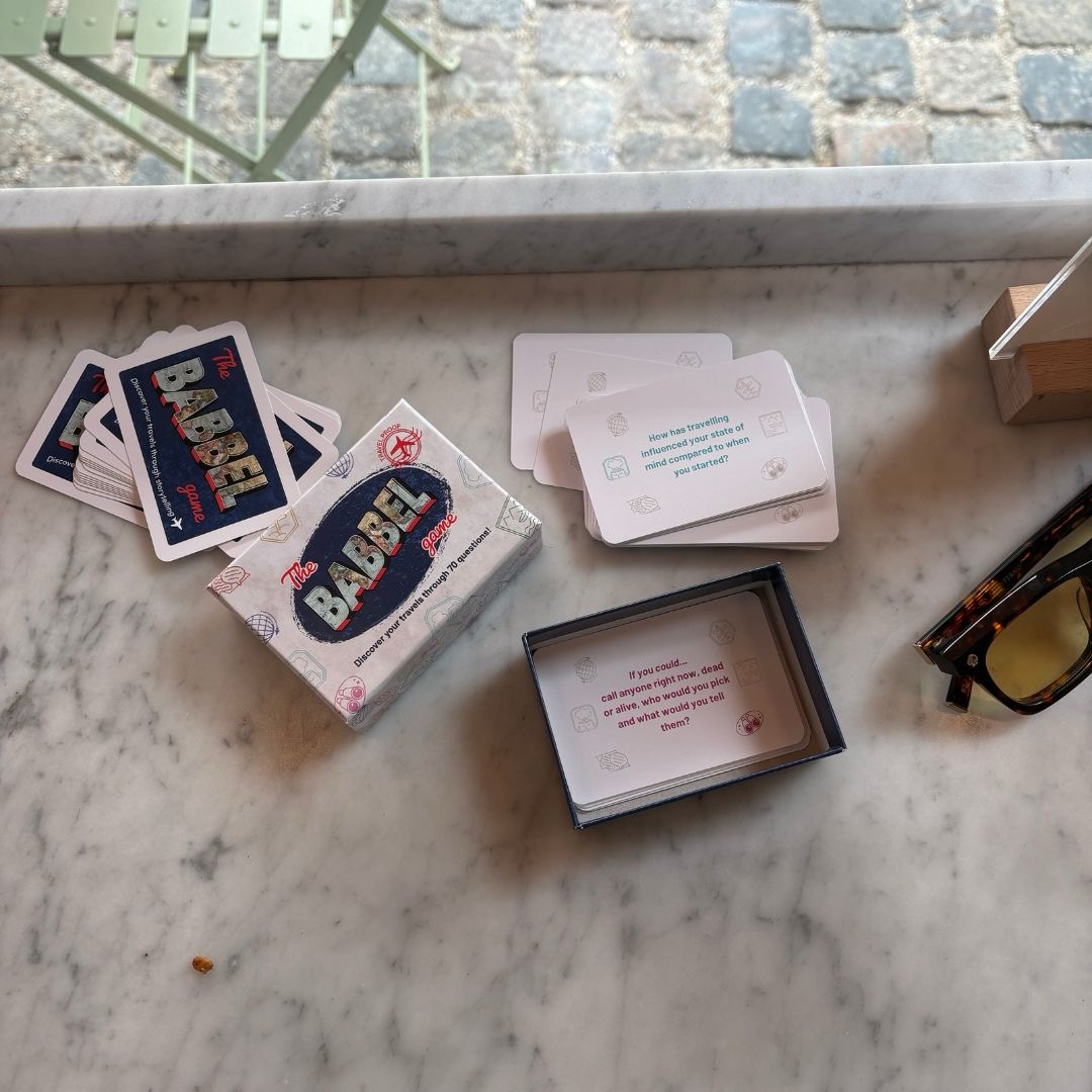 The Babbel Game box with question cards spread on a marble café table